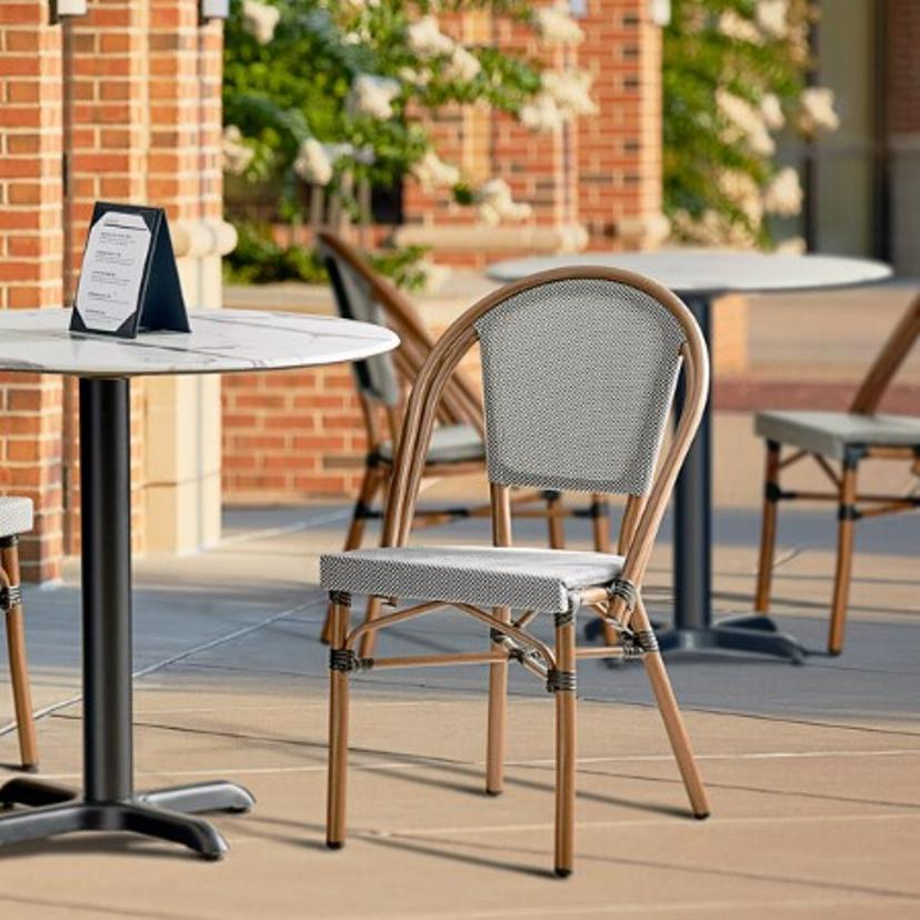 fancy outdoor table and chair with brick walls and flowering ornimental trees in the background